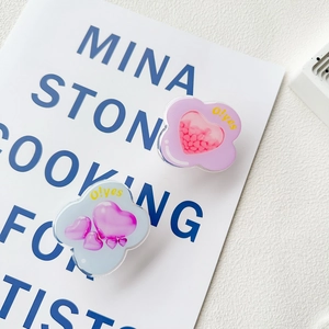 Close-up of acrylic heart phone grips with wavy edges on an artistic book background