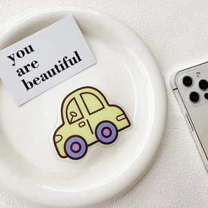 Detail of yellow car shaped acrylic phone grip on a white ceramic plate with card