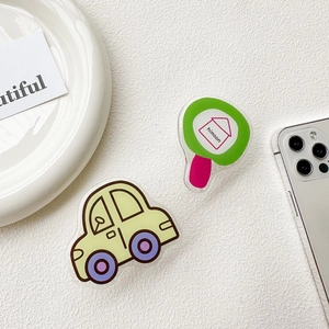 Close-up of cute yellow car and green magnifying glass acrylic phone sockets on a desk