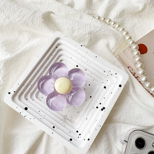 Detailed close-up of a purple flower phone grip on a white decorative tray with pearls