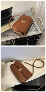 Close-up of brown faux leather shoulder bag with gold clasp shown in a lifestyle setting