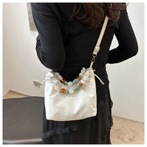 Detail of marble pattern bucket bag with multi-color beaded handles and drawstring closure