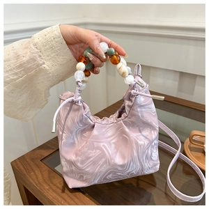 Detail of pink marble bucket bag with colorful beaded handle and drawstring closure