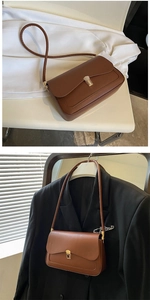 Close-up of brown leather bag featuring a gold metal buckle and fine stitching detail