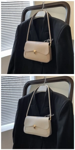 Detail of light beige leather shoulder bag with gold metal buckle and refined stitching