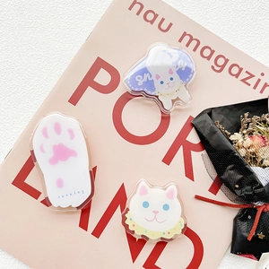 Detail of three acrylic cat phone grips showing transparent cat paw and white kitty designs