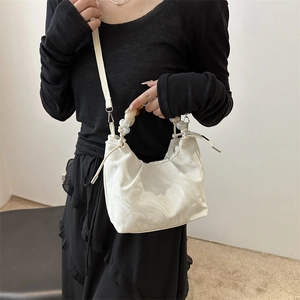 White marble pattern bucket bag with resin bead handle shown on a black outfit