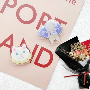 Close-up of cute white acrylic cat phone stands with blue eyes on a pink background