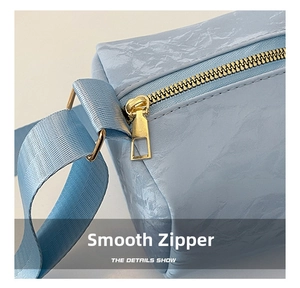 Macro detail of smooth gold metal zipper on light blue marble texture faux leather bag