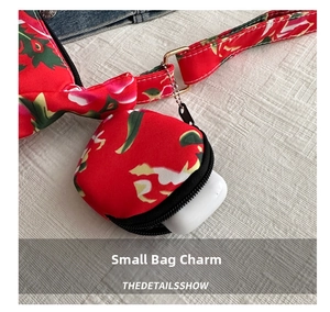 Close-up of a small floral pouch charm attached to a red canvas tote bag for earbud storage