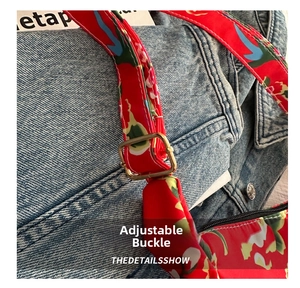 Close-up of golden adjustable buckle on floral red nylon strap over denim background