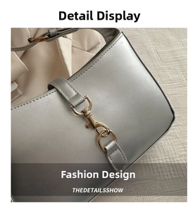Macro shot of silver pearl leather handbag featuring a signature gold piston lock detail