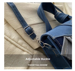 Detail of adjustable silver metal buckle and denim fabric stitching on the crossbody bag