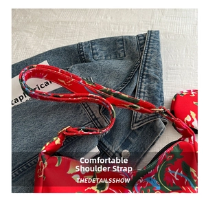 Detail of adjustable shoulder strap with golden buckles on a red floral crossbody bag