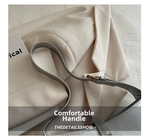 Close-up of gray leather shoulder bag with fine stitching and gold metal buckle detail