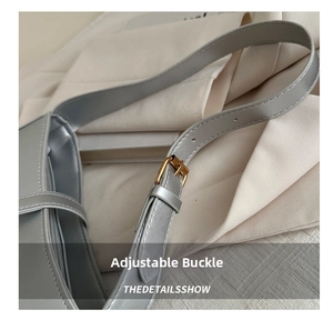 Close-up of adjustable golden buckle and stitched leather strap on a silver handbag