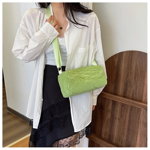 Detail of light green cylinder crossbody bag featuring pleated texture and wide strap