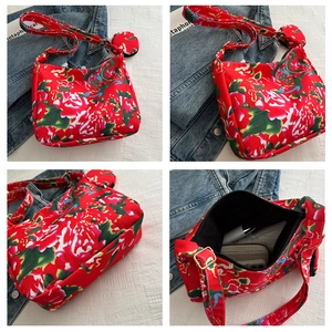 Detail view of floral crossbody bag showing red rose print, interior pocket, and round coin purse