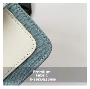 Detail of blue denim fabric and white leather stitching on a retro crossbody bag