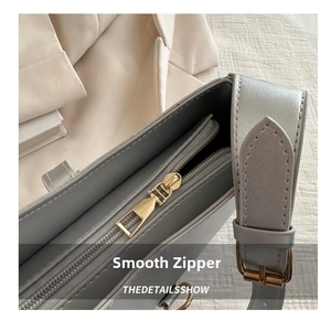 Detail view of smooth metal zipper and adjustable hardware on a minimalist leather bag