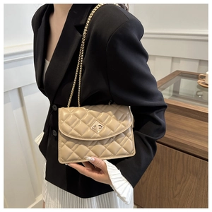 Detail of beige quilted flap bag featuring a gold chain strap and metal twist lock closure
