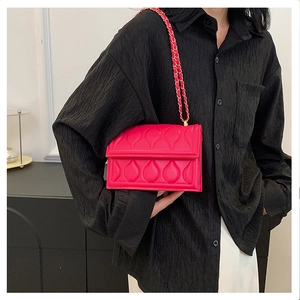 Macro detail of the bright rose pink quilted PU leather and gold chain strap of the bag