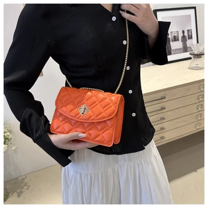 Close-up of orange quilted crossbody bag with gold chain strap and square metal lock