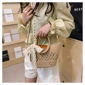 Detail of woven straw tote bag with large lace bow and leather cover on art shelf