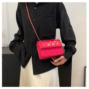 Detail of magenta square bag featuring heart-shaped quilting and gold chain strap