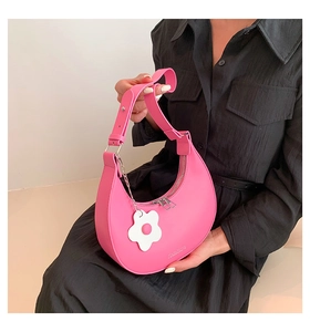 Dettaglio borsa a mezzaluna rosa acceso con zip argento e ciondolo a fiore