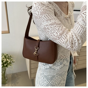 Detail of vintage matte brown shoulder bag featuring gold piston lock hardware on a model