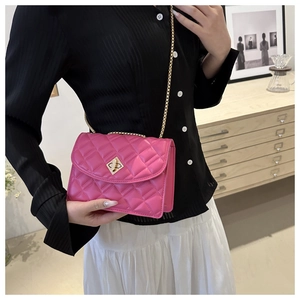 Magenta quilted crossbody bag with gold chain strap shown on a model in a home setting