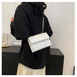 Detail showing white PU leather bag with heart embossed texture and gold chain strap