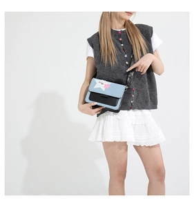 Close-up of denim crossbody bag with contrast stitching and star-shaped embroidery detail