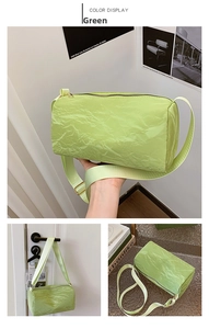 Detail view of a green cylinder pillow bag featuring pleated fabric and an adjustable strap