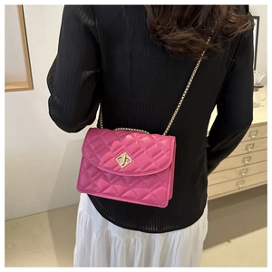 Rose pink quilted chain bag with gold buckle shown on shoulder in a cozy home setting