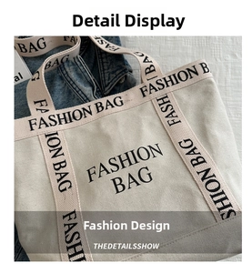 Close-up of cream canvas tote bag with black Fashion Bag lettering and shoulder strap