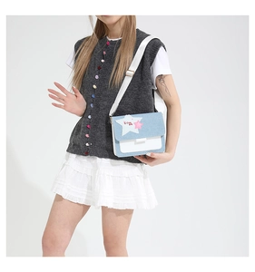 Detail of blue denim and white leather crossbody bag with star patch and wide strap