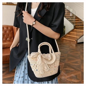 Close-up of woven straw tote bag with lace bow decoration and elegant pearl button closure