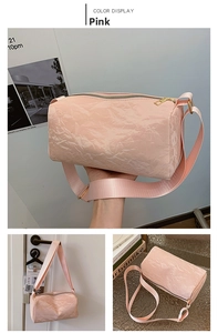 Macro shot of pink cylindrical pillow bag with unique wrinkled texture and gold hardware
