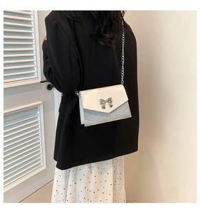 Dettaglio borsa bianca con base glitter argento e chiusura a fiocco in metallo lucido