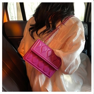 Detail of rose pink quilted leather bag with elegant gold chain strap in a car setting