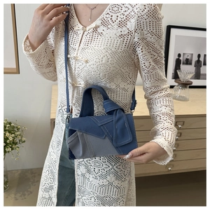 Detail of denim patchwork crossbody bag with contrast stitching and knotted handle