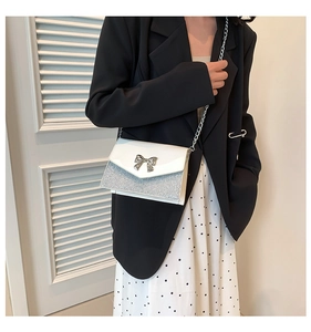 Dettaglio borsa a tracolla elegante in paillettes bianche e argento con fiocco in metallo