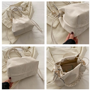 Detail view of beige pleated bucket bag with braided handle and drawstring closure