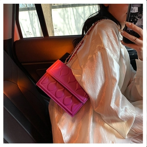 Detailed close-up of bright pink quilted crossbody bag with golden chain and drop pattern