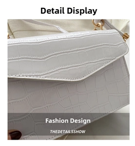 Close-up of white crocodile pattern patent leather handbag with gold metal hardware