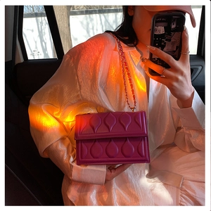Detailed view of purple quilted handbag with teardrop stitching and chain strap
