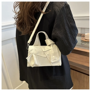 Detail of cream canvas crossbody bag with unique layered folding and knot design