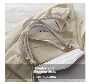 Detail of white crocodile pattern shoulder bag with golden metal buckle and thin strap